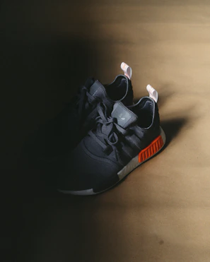 Close-up of sleek black sneakers with orange accents on a clean white background.