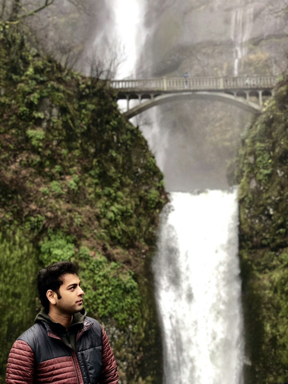 man standing front of water falls at daytime