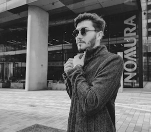 A stylish man confidently adjusting his blazer in a modern urban setting.