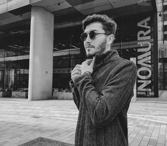 A stylish man confidently adjusting his blazer in a modern urban setting.