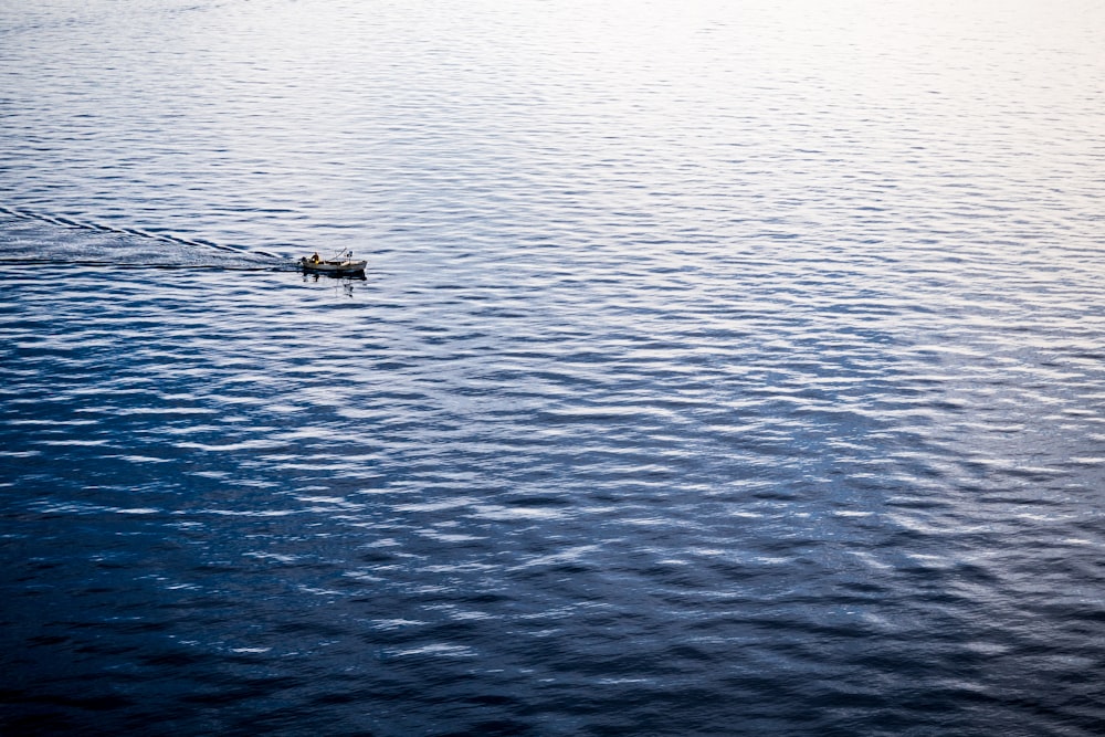 people riding boat floating on body of water during day