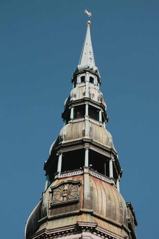 gray and brown clock tower during day in St. Peter's Church Latvia