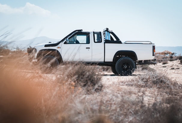 A reliable 4x4 pickup truck parked on a rugged trail with mountains in the background.