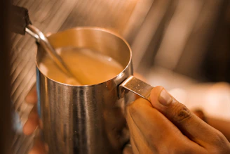 Detailed shot of a steaming pitcher creating perfect milk foam texture.