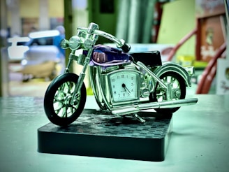 A detailed miniature classic motorcycle model on a wooden shelf.