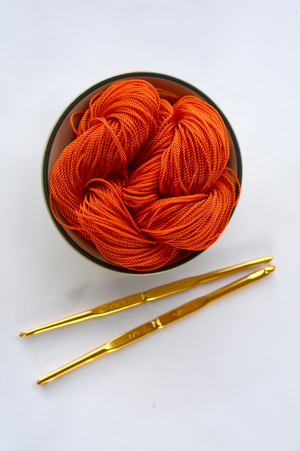 orange yarn on round white bowl
