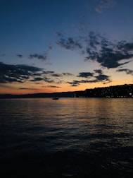 A scenic view of Ghana’s coastline with a small boat sailing at sunset.
