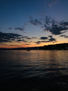 A scenic view of Ghana’s coastline with a small boat sailing at sunset.