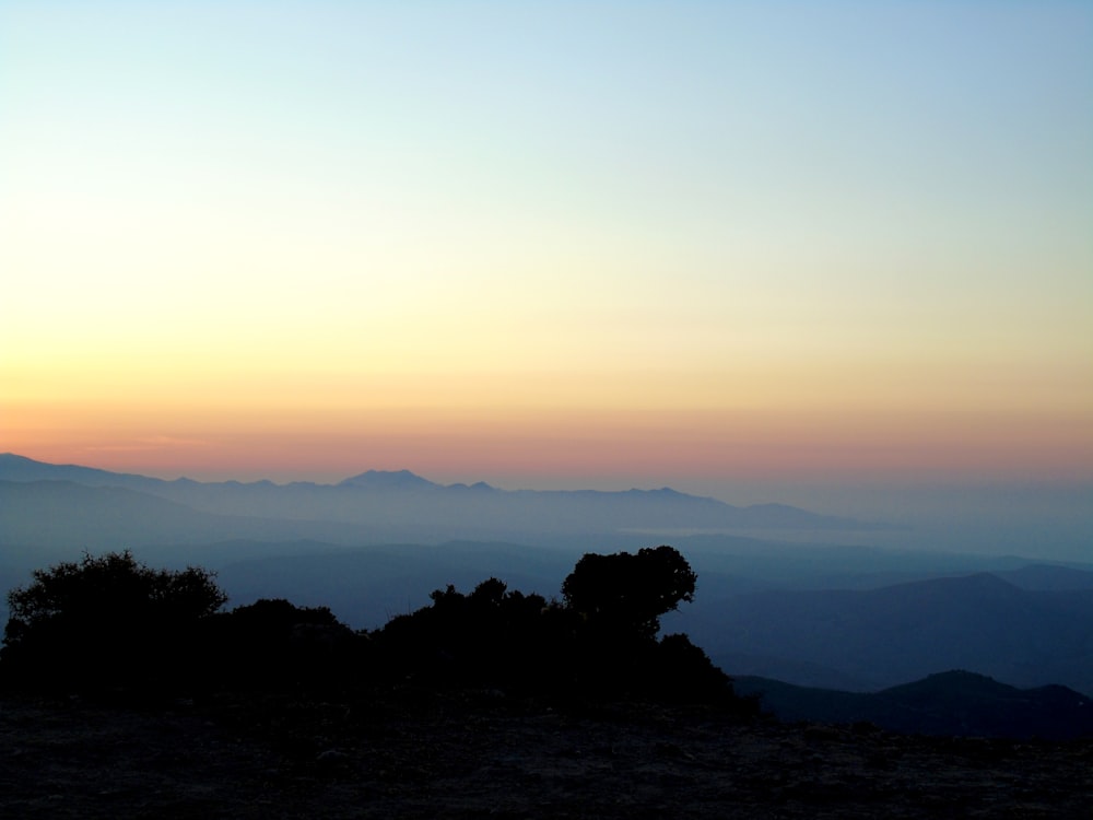 the sun is setting over a mountain range