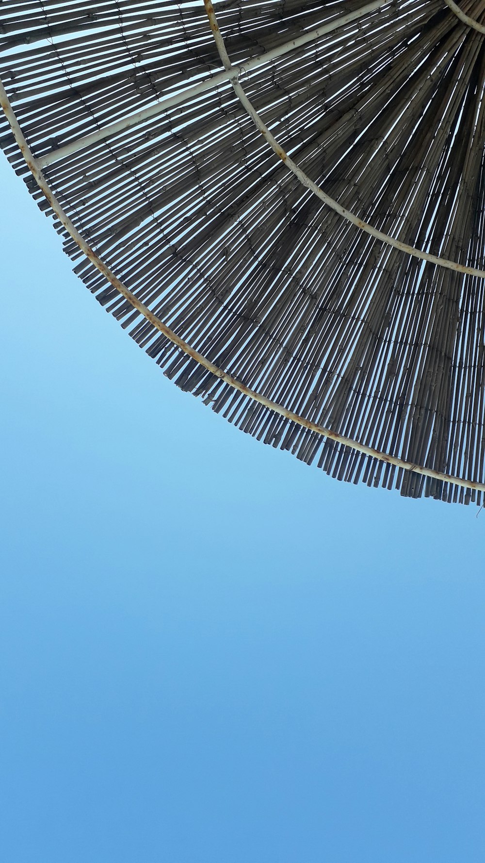a close up of a straw umbrella against a blue sky
