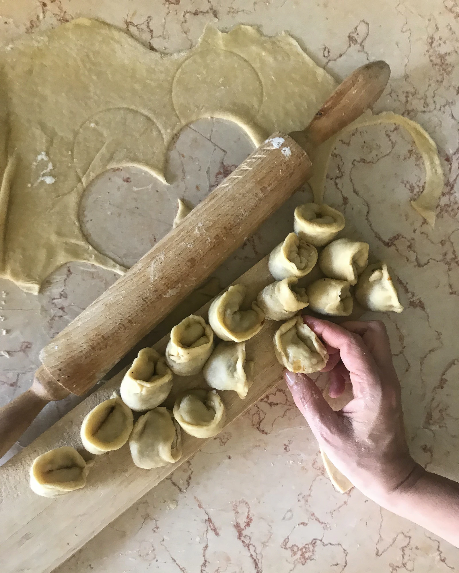 Filled pasta and a rolling pin on a floured board