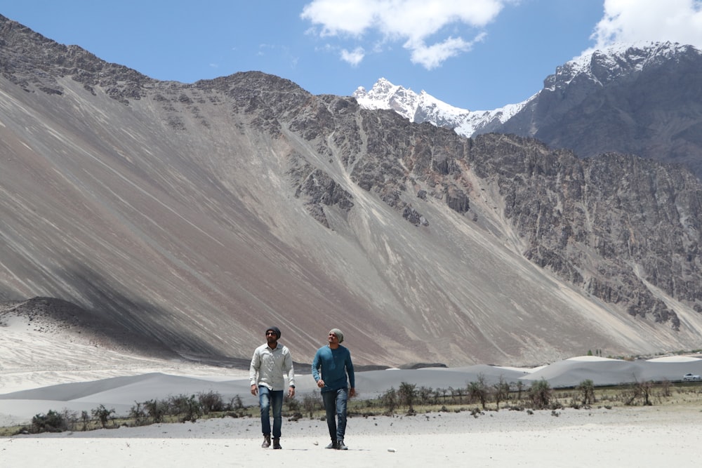 Zwei Männer gehen auf offenem Feld in der Nähe eines Berges spazieren