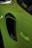 A close-up of a bright green car showing the area around the side air intake and door handle. The car's paint reflects light, and a window decal with text is visible on the edge of the window.