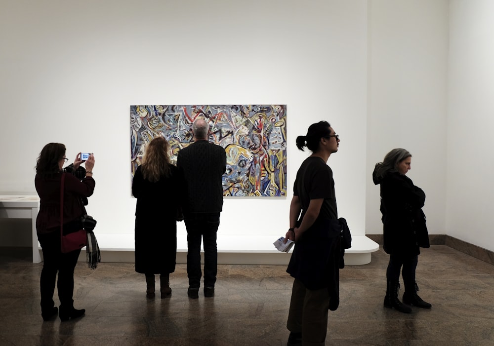 um grupo de pessoas em pé na frente de uma pintura