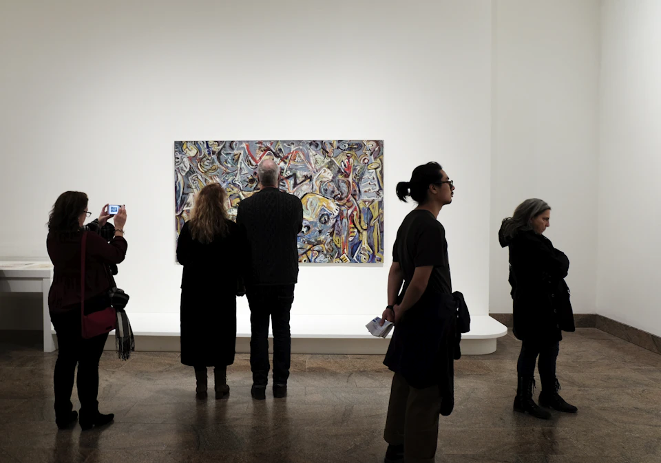 Visitors looking at paintings in a museum gallery