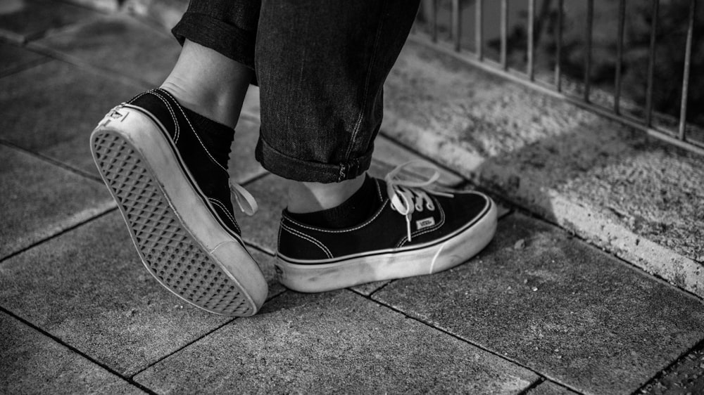 grayscale photo of person wearing black sneakers
