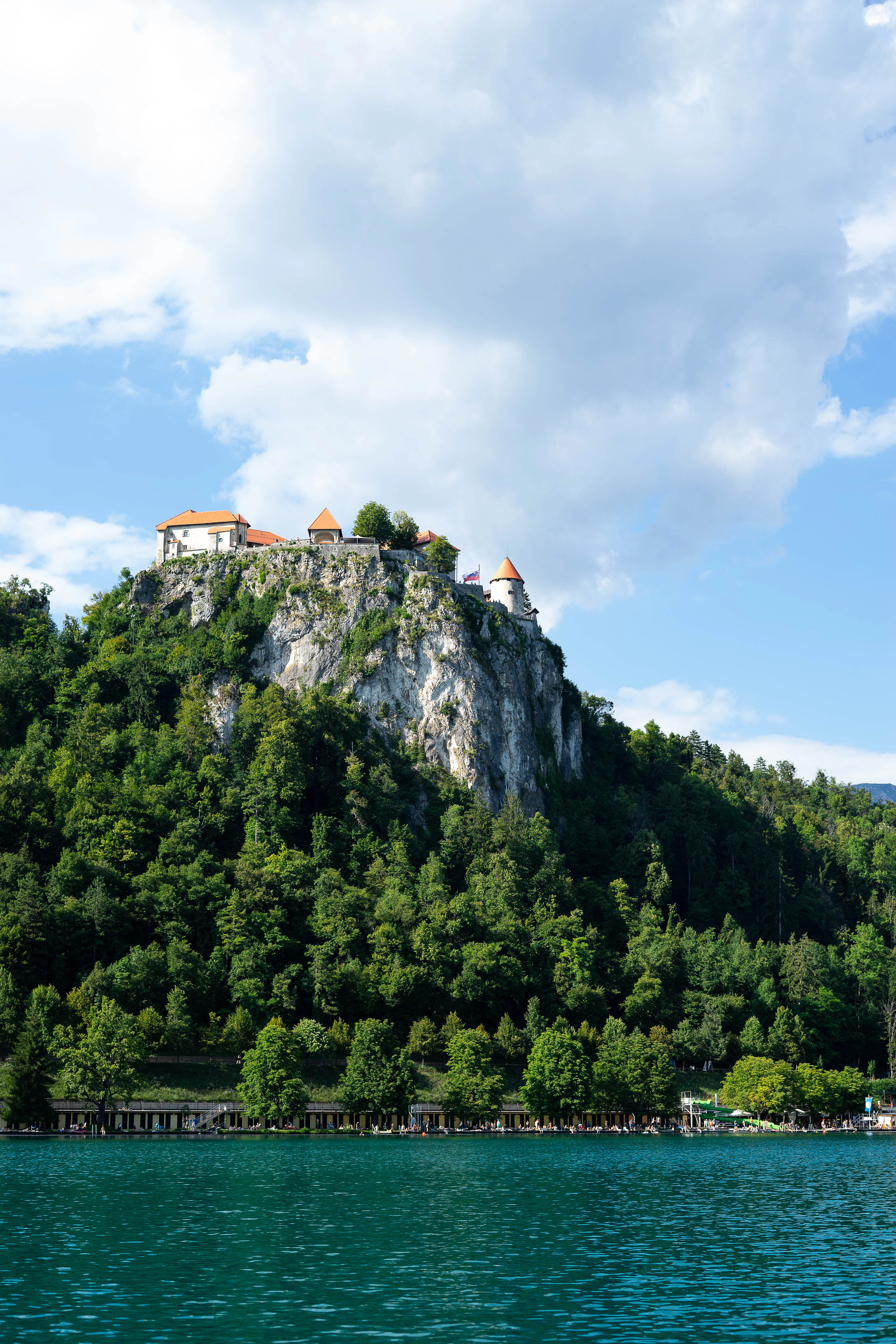 Bled Castle perched on its wooded limestone cliff above the green water of Lake Bled