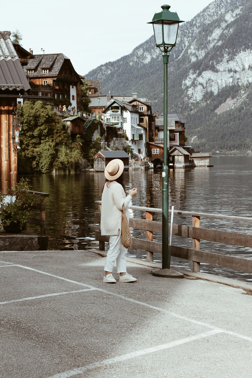 woman wearing white jacket and white track pants looking at green post lamp