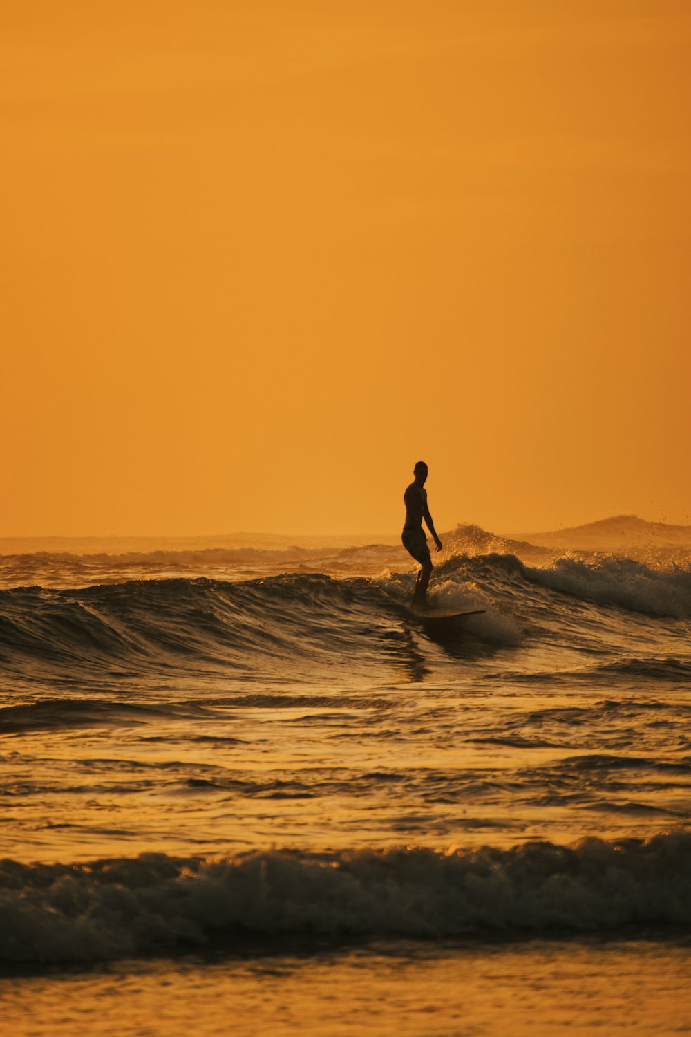 silhouette of person riding on white surfboard