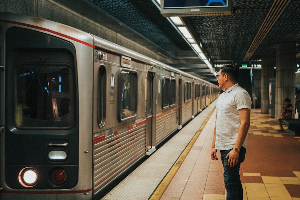 man wearing white dress shirt standing near gray train