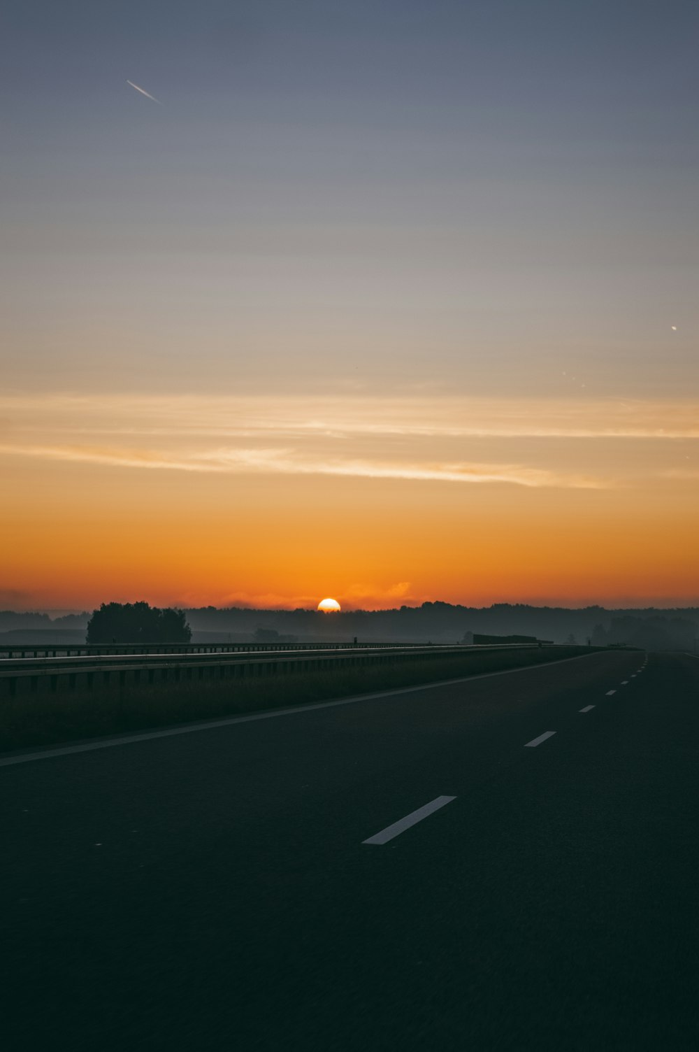 the sun is setting on the horizon of a highway
