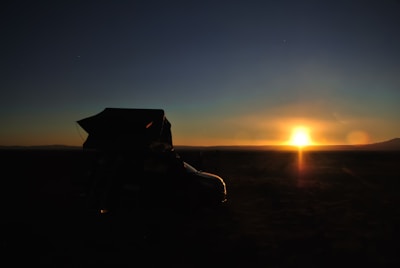 the sun is setting behind a vehicle in the desert