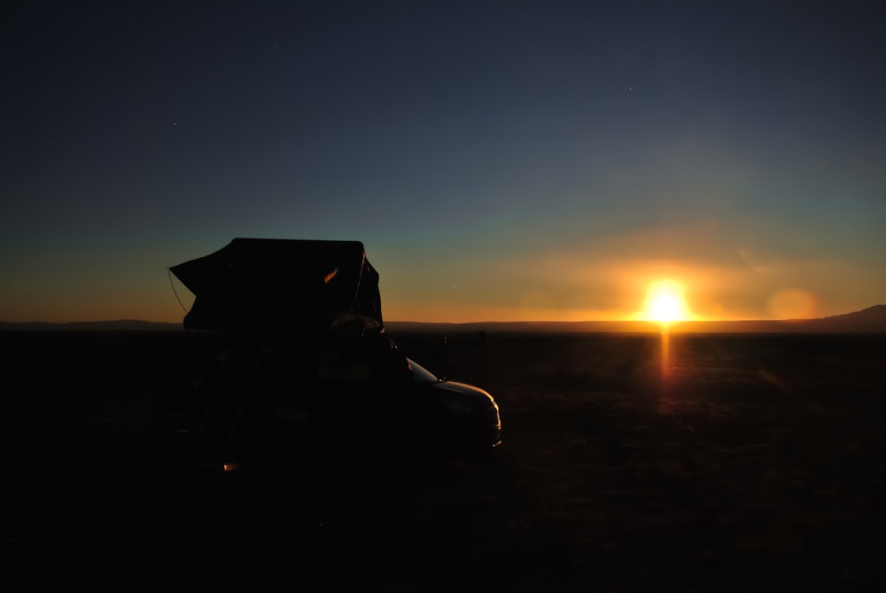 the sun is setting behind a vehicle in the desert