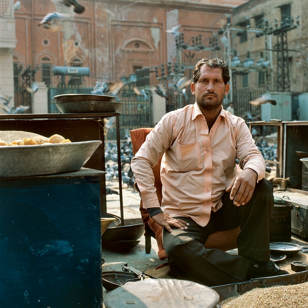 man sitting and glaring near flock of pigeons