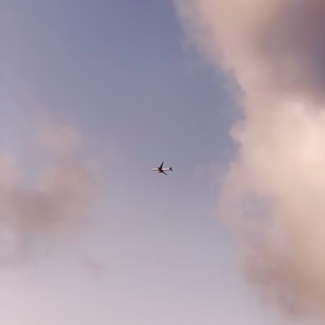 An airplane flying over clouds during a bright sunrise.