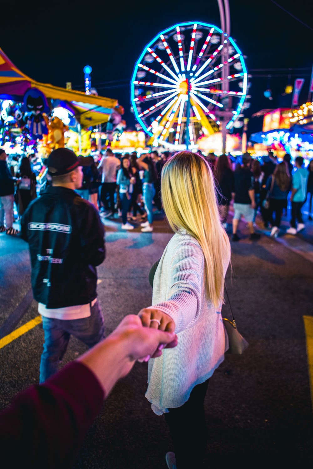 woman wearing white long-sleeved top across ferris wheel during nighttime