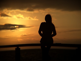 silhouette of woman standing near beach line