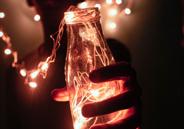 person holding bottle with string lights