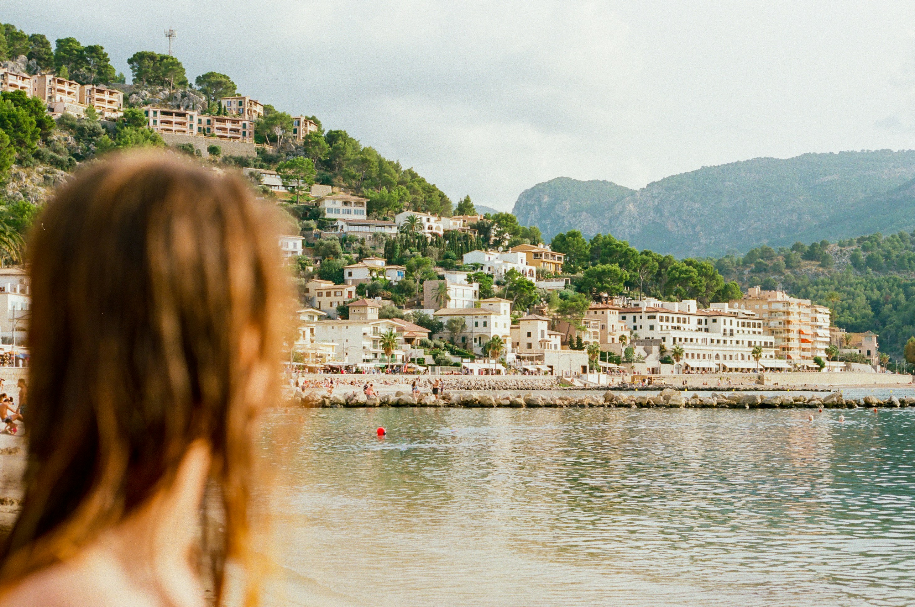 woman on shore looking at the buildings on island during day