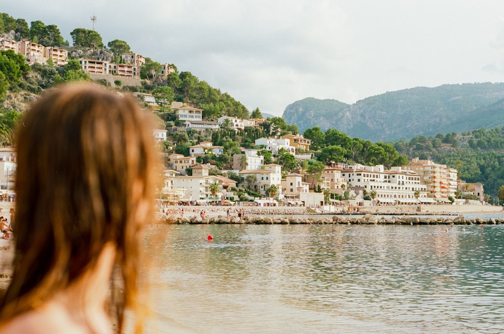woman on shore looking at the buildings on island during day