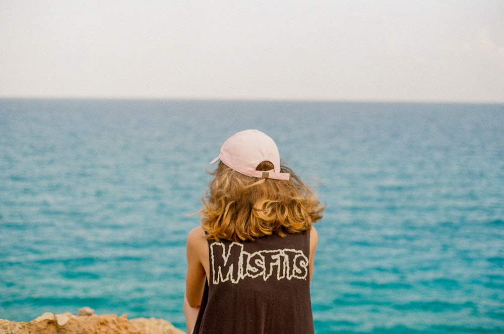 person wearing sleeveless top facing the ocean during day