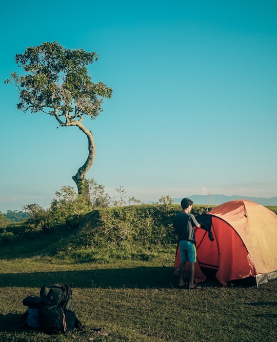 man standing in front of orange camping tent in Samosir Indonesia