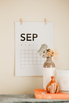 a desk with a calendar and a vase of flowers