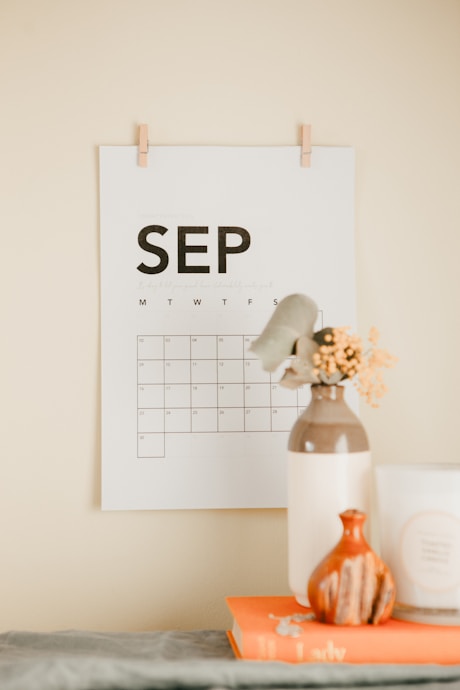 a desk with a calendar and a vase of flowers