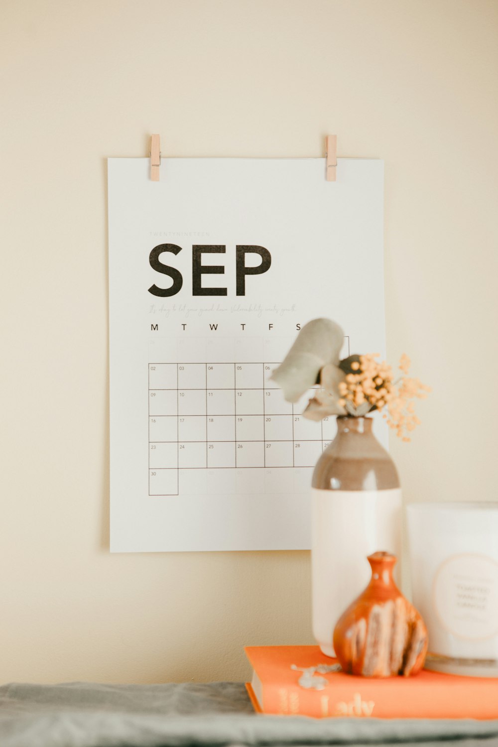 a desk with a calendar and a vase of flowers