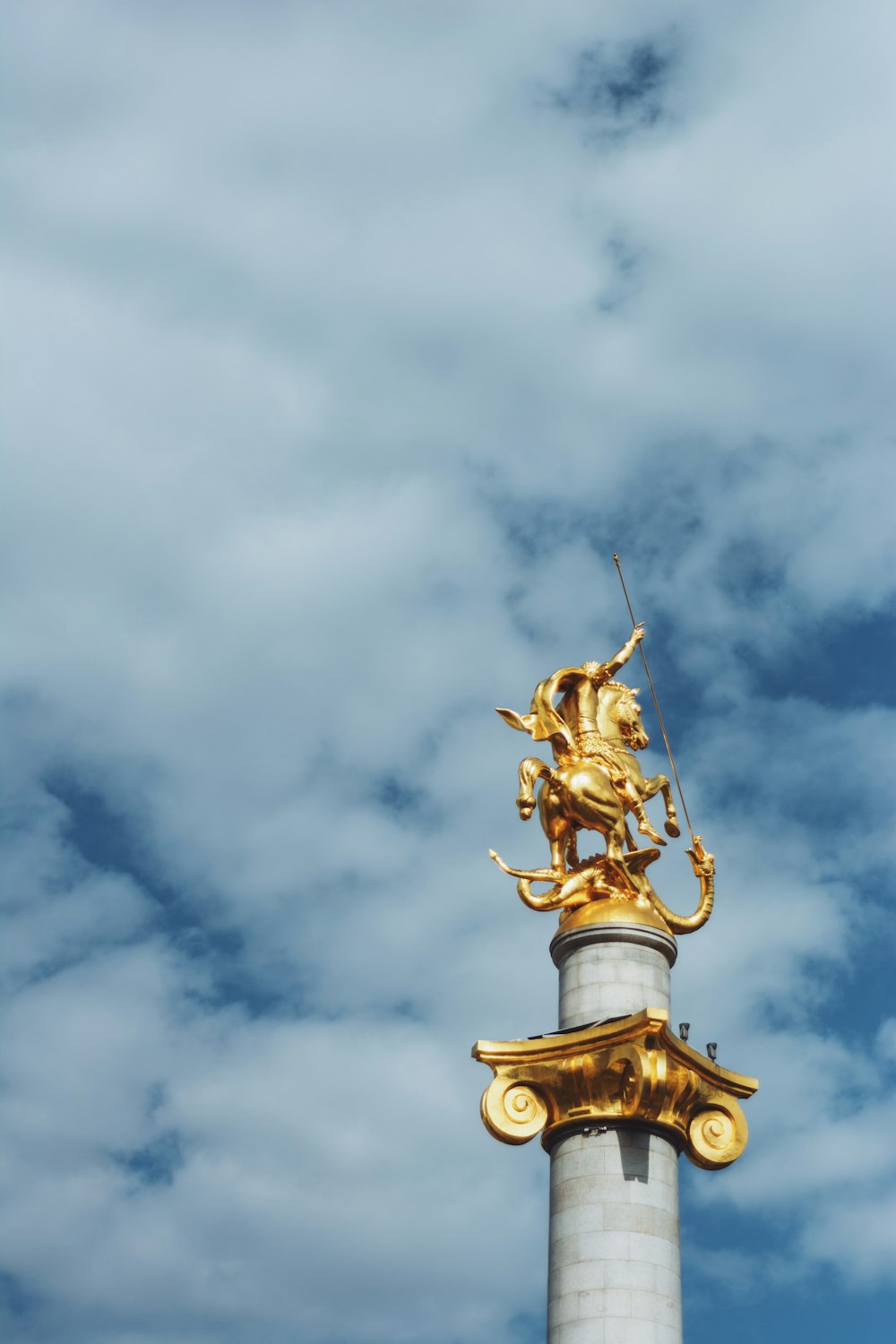 gold and gray person riding horse tower statue during day