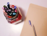 Close-up of hands holding a journal and pen, surrounded by colorful wellness products.