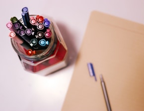 Close-up of elegant pens and notebooks with a soft sky blue background.