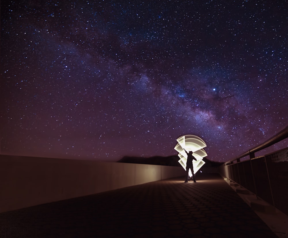 man on top of the building waves light torch under starry night