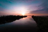 A peaceful sunset casting warm hues over a tranquil cenote landscape.