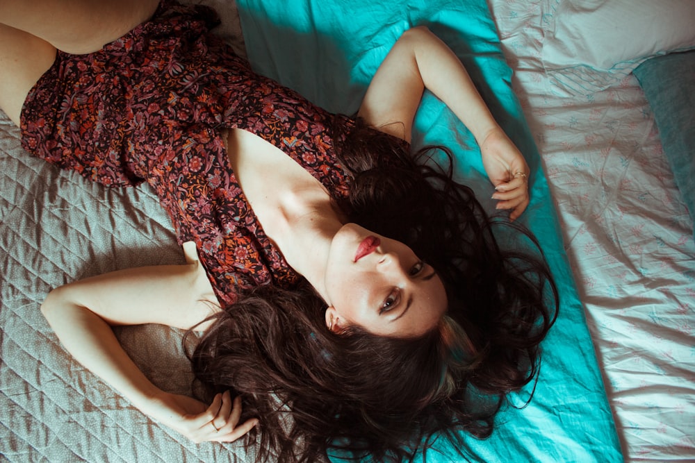 a woman laying on top of a bed in a dress