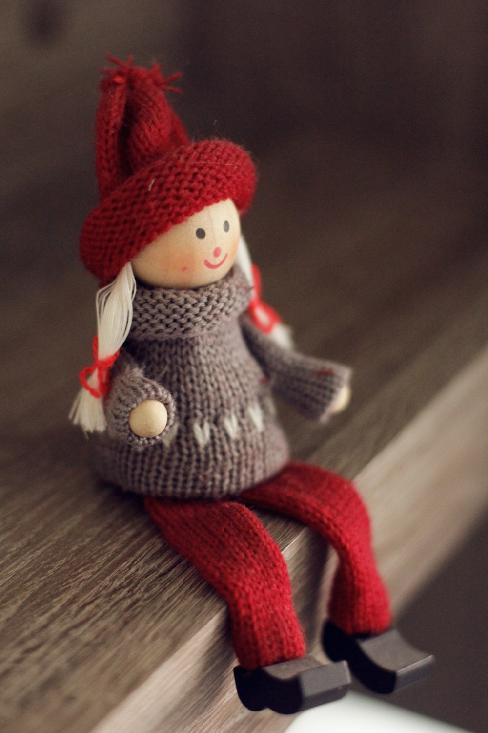 doll wearing red and gray sweater on wooden plank