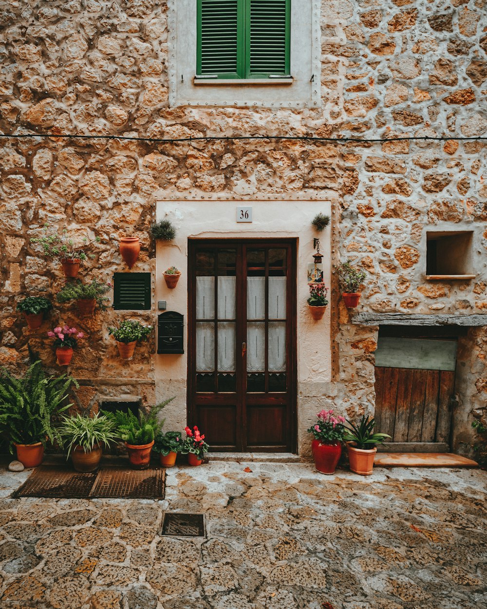 a stone building with potted plants and a door