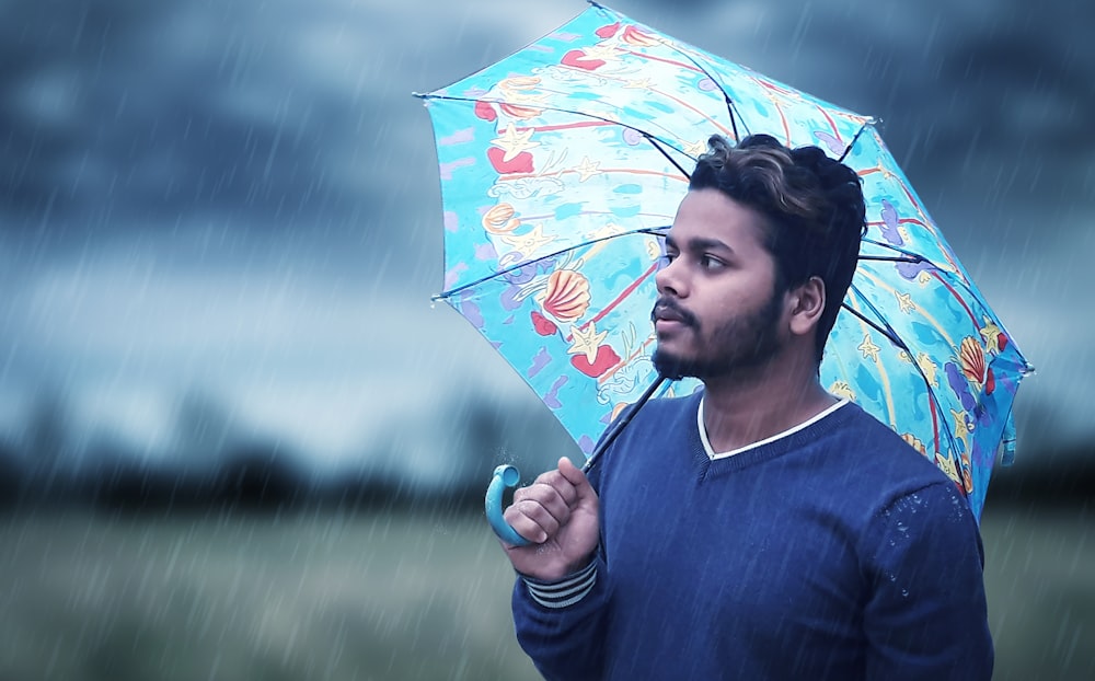 shallow focus photo of man holding blue umbrella