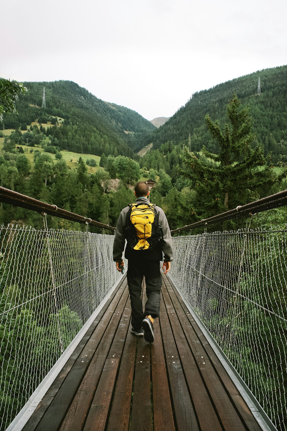 man walking on bridge near trees during day