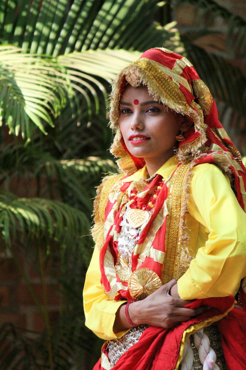 woman wearing red and yellow long-sleeved dress standing near green plant